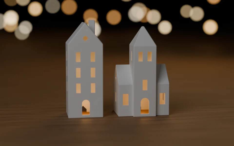 Schmales Stadthaus und Turmhaus in Weiß mit warm leuchtenden Fenstern auf einem Holztisch, im Hintergrund unscharfe Lichter. Holztisch, Lichter und das Licht in den Fenstern sind Dekoration und nicht enthalten.